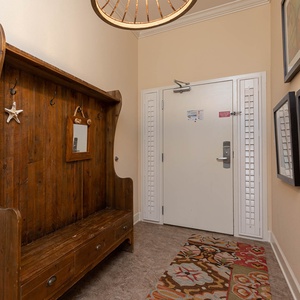 This welcoming entryway features a rustic wooden bench, a mirror, and colorful artwork, setting a charming tone for your stay