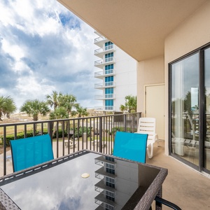 Relax at the outdoor dining set with colorful chairs, enjoying views of palm trees, beach, and the nearby pool area