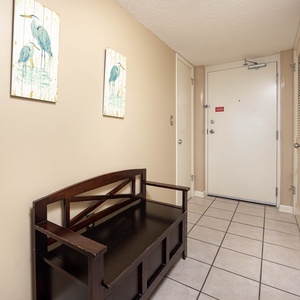 Welcoming entryway features a wooden bench, decorative bird artwork, and tiled flooring leading to the main living space