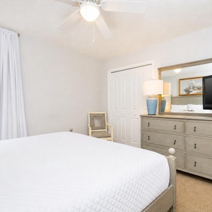 Unwind in the guest bedroom with a queen bed, soft linens, and a dresser with a TV