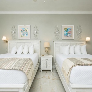 Unwind in this serene guest bedroom featuring two plush beds, stylish decor, and charming artwort