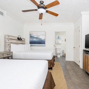 Relax in the comfortable guest room featuring two double beds, a large TV, and stylish decor for your enjoyable stay