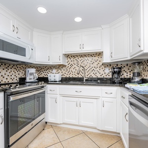 This kitchen features stainless appliances, granite countertops, and a stylish mosaic backsplash for delightful cooking