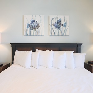 Tranquil master suite featuring a plush king bed, decorative pillows, and fish-themed artwork