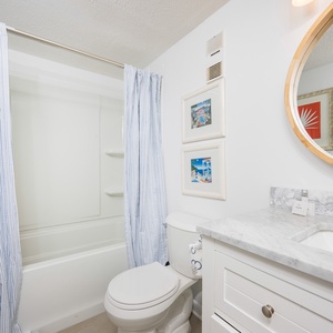 The master bathroom features a stylish countertop, a round mirror, and charming artwork, creating a refreshing atmosphere