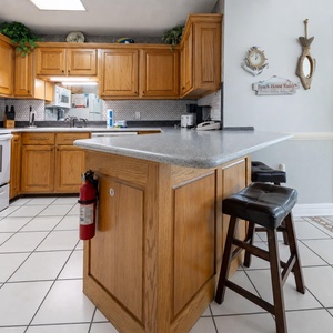 Warm wood cabinetry complements the granite countertop in this inviting kitchen area, featuring a breakfast bar with seating