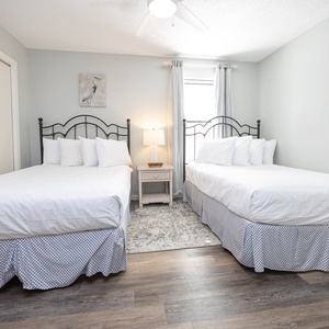 Inviting guest bedroom featuring two double beds, soft linens, and natural light streaming through the windows