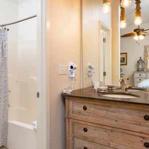 Master bath featuring a tub/shower combo, rustic wooden vanity, and stylish lighting, with a view into the master suite