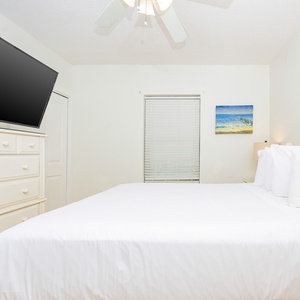 Cozy guest bedroom featuring a queen bed, a flat-screen TV, and coastal artwork to enhance your stay