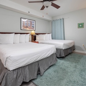 This guest bedroom features two comfortable full beds, a cozy rug, and a flat-screen TV for your entertainment