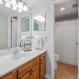 Bright master bath featuring a vanity with wooden cabinetry, a large mirror, and a tub/shower combo behind a curtain