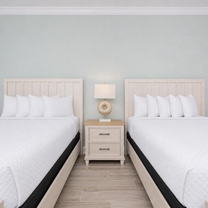 Rest in this relaxing guest room featuring queen beds with plush linens, a stylish lamp, and soft decor
