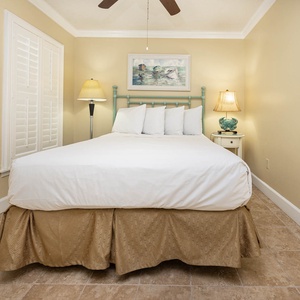 The guest bedroom features soft beige walls, elegant lighting, and a comfortable queen bed with decorative pillows