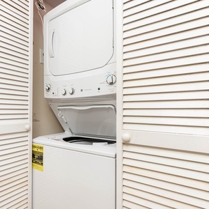 This laundry area features a stacked washer and dryer behind louvered doors, adding convenience for your stay