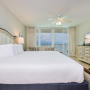 Spacious master bedroom featuring a king bed, elegant decor, additional twin bed, and a stunning view from the balcony