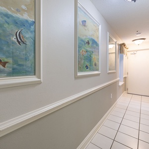 Colorful fish-themed artwork adorns the walls of the hallway, leading to the entrance of the vacation rental
