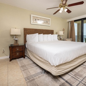 The master bedroom features a king bed, charming decor, and a TV, with a lovely view from the balcony