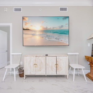 Enjoy the inviting living space with a large TV, stylish coastal decor, and comfortable seating for relaxation