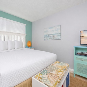 Master bedroom featuring a plush queen bed, vibrant decor, and a flat-screen TV for cozy relaxation