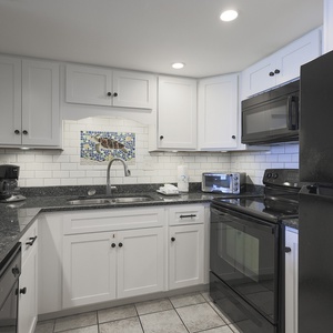 This kitchen features black appliances, granite countertops, and a colorful backsplash, perfect for meal prep and gatherings