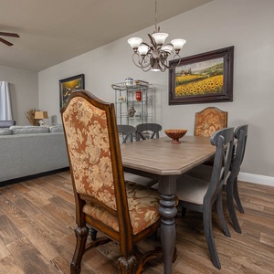 Elegant dining area features a wooden table surrounded by ornate chairs, with a view of the beach through large windows