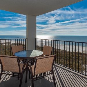 Balcony seating for four offers a serene view of the shimmering gulf and the inviting beach below