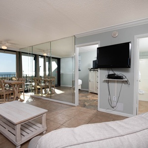 This inviting space features a cozy seating area with a view of the beach and a dining table perfect for meals