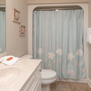 Enjoy a refreshing shower this guest bath, where coastal decor and soft towels create a tranquil start to your beach day