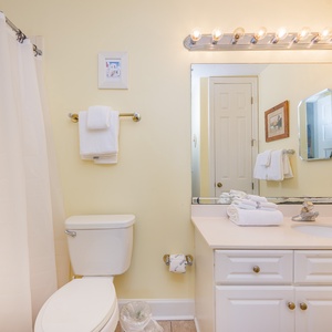 Fresh towels await in the master bath where you refresh under warm lighting after a day on the coast