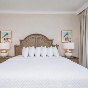 Enjoy this spacious master bedroom with a king bed, elegant lamps, and lovely coastal artwork