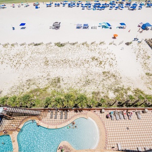 Enjoy the vibrant gradual entry pool area with a waterslide, surrounded by lounge chairs and views of the beach beyond