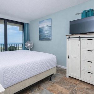 Inviting king master suite with a cozy bed, a stylish dresser, and stunning beachfront views through large windows