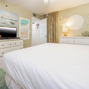This cozy bedroom features soft beach-themed decor, a TV, and a welcoming atmosphere perfect for relaxation