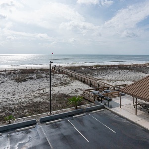 This view showcases a serene beachfront with a wooden walkway leading to the sand, perfect for a relaxing getaway