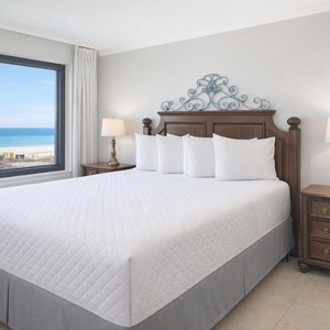 King master bedroom featuring a plush bed and stunning beachfront views through large windows