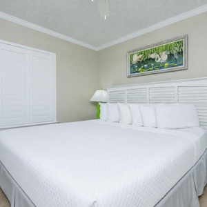 Relax in this serene guest bedroom featuring a king bed, soft linens, and cheerful artwork for a restful night's sleep