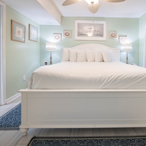 Cozy master bedroom featuring a plush white king bed, soothing green walls, and a cozy atmosphere for relaxation