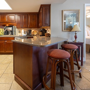 Rich wood cabinetry complements the modern kitchen with a breakfast bar and seating, leading to the master suite