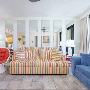 Relax on the plush striped sofa, engaging in cheerful conversations as sunlight brightens the vibrant living area