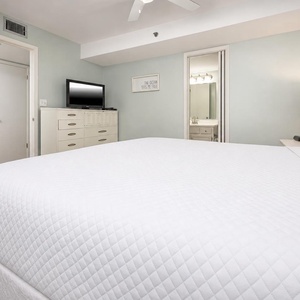 This cozy bedroom features a plush bed, a flat-screen TV, and an ensuite bathroom with a stylish vanity