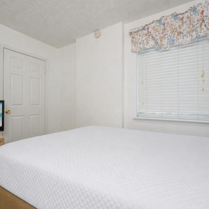 This cozy bedroom features a comfortable bed with stylish bedding and a TV for entertainment, perfect for a relaxing stay