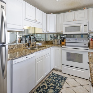 Granite countertops and white cabinetry in this inviting kitchen, featuring a spacious design for beach meals