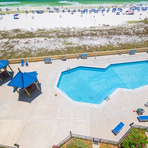 Watch children splash in the pool as you soak in the sunshine beside rows of lounge chairs nearby the beach coast