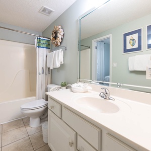 Refresh in the guest bathroom featuring a spacious tub-shower, soft towels, and charming coastal decor for your comfort