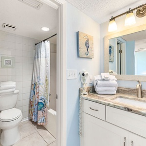 Bright master bath featuring a tub/shower combo, elegant countertop, and decorative seahorse artwork for a refreshing vibe