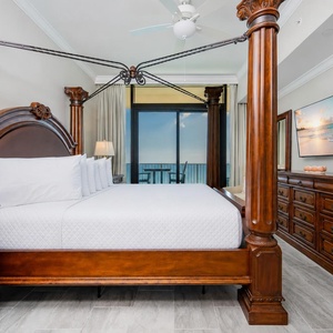 Relax in this elegant king master suite featuring a four-poster bed, stylish decor, and beachfront balcony access