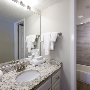 The master bath features a granite countertop, colorful shower curtain, and fresh towels for a refreshing experience