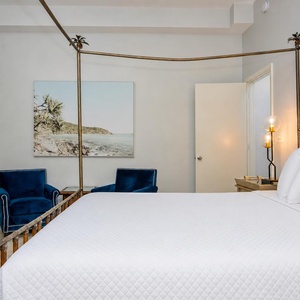 Stylish master suite featuring a four-poster king bed, plush pillows, and cozy seating for unwinding after a beach day
