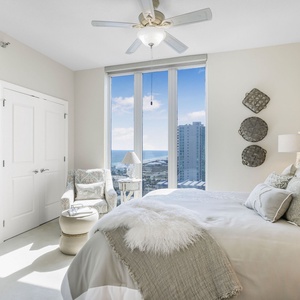 This bedroom features a plush bed with soft pillows, stylish decor, and a stunning beach view through large windows