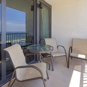 This balcony features comfortable seating and a table, perfect for enjoying the beachfront view